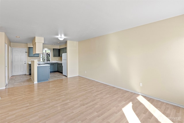 unfurnished living room with baseboards and light wood finished floors