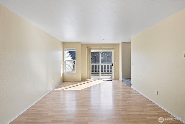 unfurnished room with light wood-style flooring and baseboards