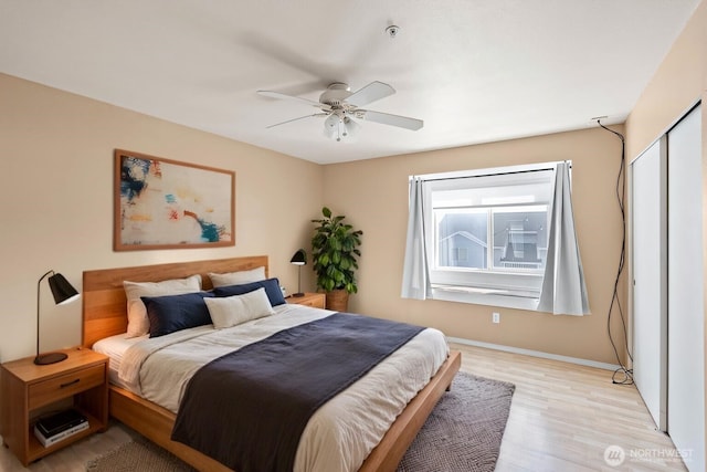 bedroom featuring light wood-style flooring, baseboards, and ceiling fan