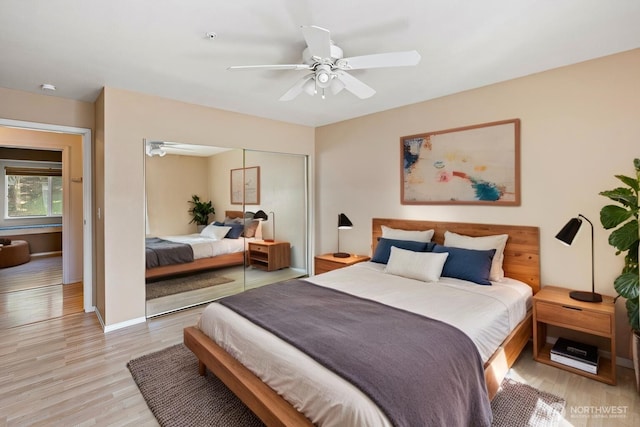 bedroom featuring a closet, light wood finished floors, baseboards, and a ceiling fan