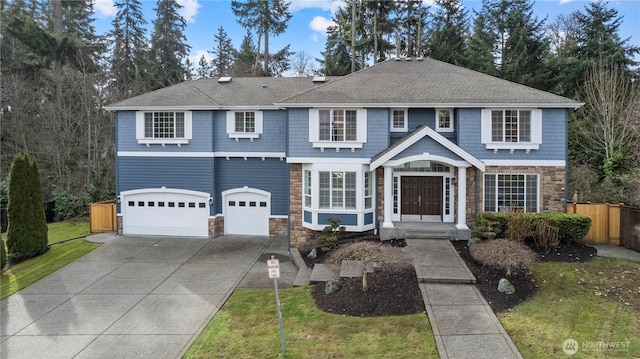 view of front of house with concrete driveway, a garage, fence, and stone siding