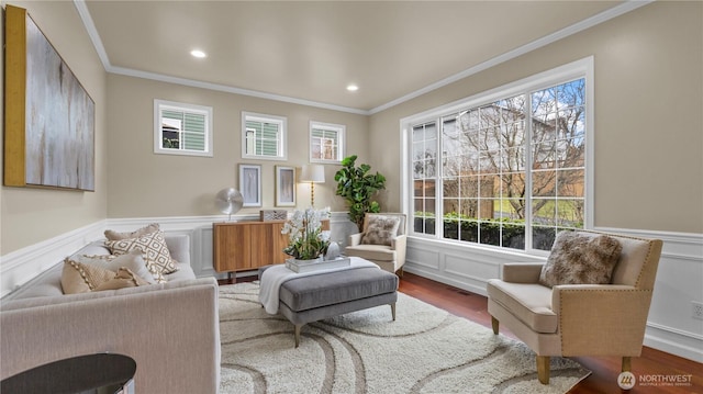 sitting room with plenty of natural light, wood finished floors, a wainscoted wall, and ornamental molding