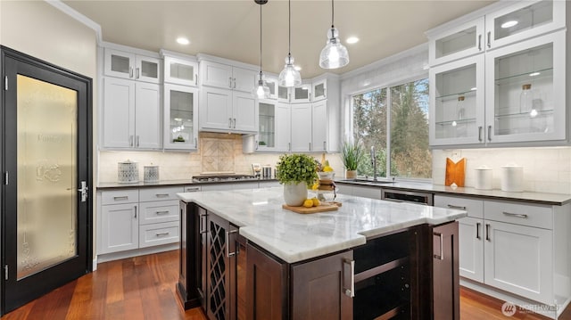 kitchen with dark wood-type flooring, beverage cooler, a sink, a center island, and hanging light fixtures