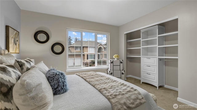 carpeted bedroom with a closet and baseboards