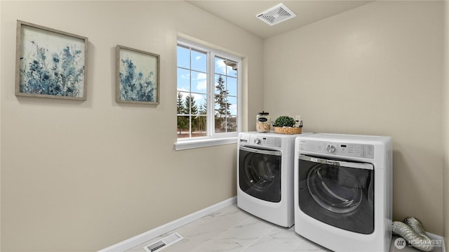 clothes washing area with washer and clothes dryer, visible vents, marble finish floor, and laundry area