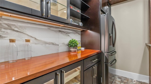 kitchen with beverage cooler, backsplash, butcher block counters, glass insert cabinets, and baseboards