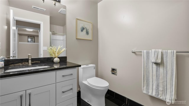 bathroom featuring vanity, toilet, visible vents, and walk in shower