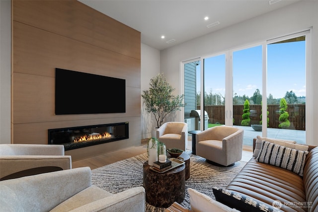 living room with wood finished floors, recessed lighting, visible vents, and a large fireplace