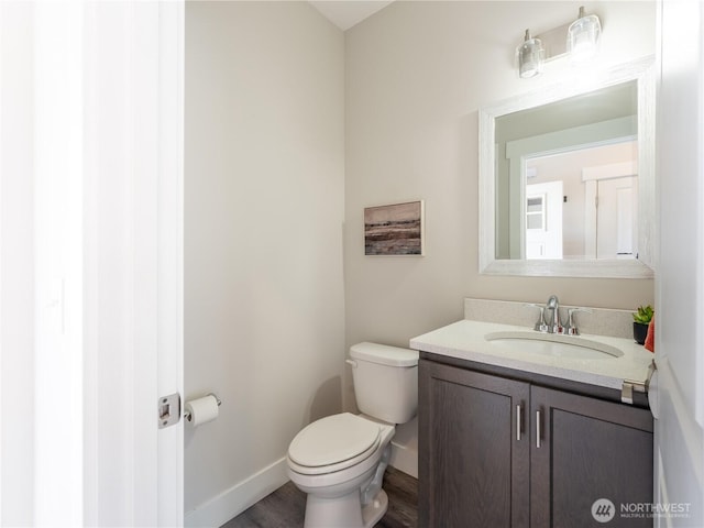 bathroom featuring baseboards, toilet, wood finished floors, and vanity