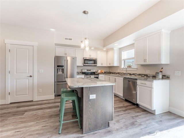 kitchen with light stone counters, visible vents, white cabinets, and appliances with stainless steel finishes