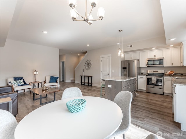 dining space with wood finished floors, visible vents, baseboards, an inviting chandelier, and recessed lighting