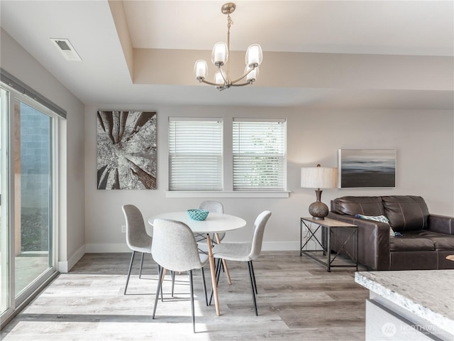 dining room with light wood-type flooring, baseboards, visible vents, and a chandelier