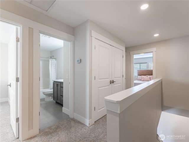 hallway featuring recessed lighting, light colored carpet, and baseboards