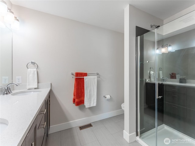 bathroom featuring visible vents, double vanity, a sink, a shower stall, and toilet