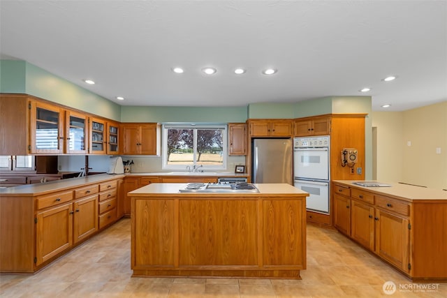 4596 Woodcock Rd, Sequim, WA 98382 - kitchen with glass insert cabinets, a center island, light countertops, appliances with stainless steel finishes, and a sink