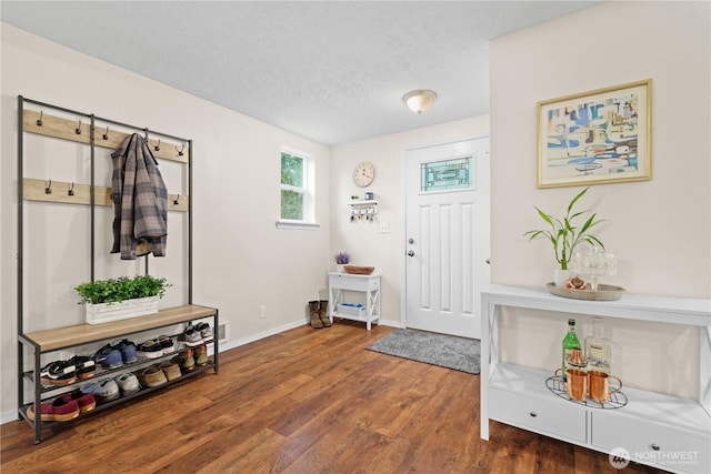 foyer with baseboards, a textured ceiling, and wood finished floors