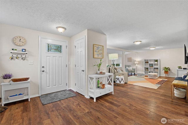 entryway with wood finished floors, baseboards, and a textured ceiling