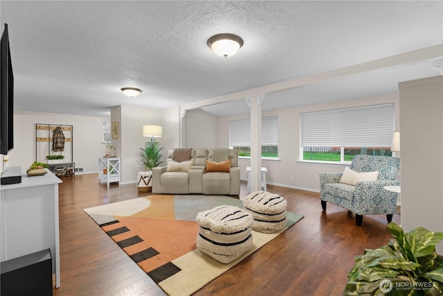 living room featuring visible vents, a textured ceiling, hardwood / wood-style floors, and ornate columns