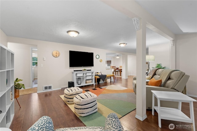 living room with visible vents, baseboards, and hardwood / wood-style flooring