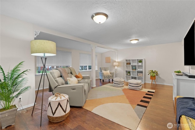 living room featuring baseboards, a textured ceiling, and wood finished floors