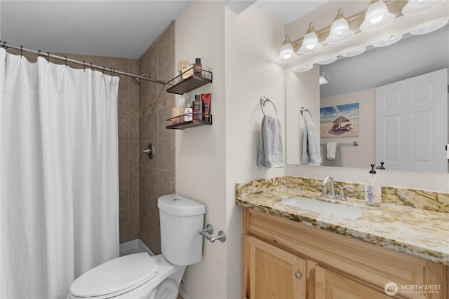 bathroom featuring a tile shower, toilet, and vanity