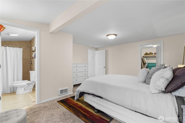 bedroom featuring visible vents, a walk in closet, baseboards, carpet, and beamed ceiling