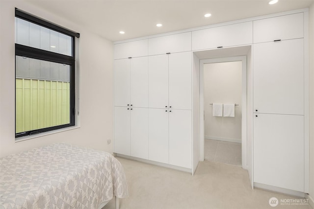 bedroom with recessed lighting, a closet, and light carpet