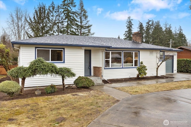 ranch-style home with a shingled roof, a garage, driveway, and a chimney