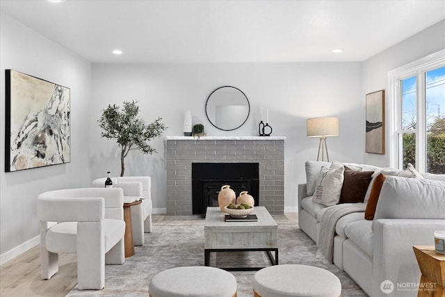 living area featuring recessed lighting, a fireplace, light wood-style flooring, and baseboards