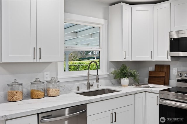 kitchen featuring a sink, light stone countertops, appliances with stainless steel finishes, and white cabinets