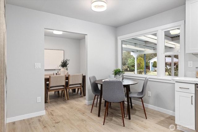 dining area with light wood-style flooring and baseboards