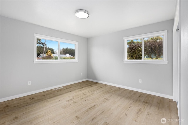 empty room with a wealth of natural light, baseboards, and wood finished floors