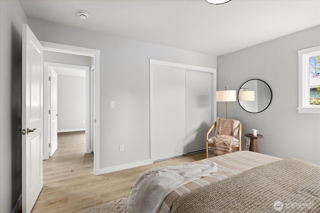 bedroom with a closet, baseboards, and light wood-style floors