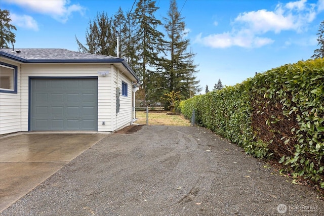 garage with concrete driveway and fence