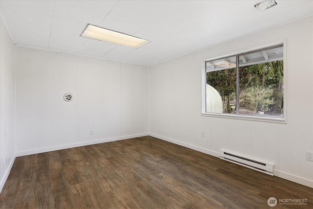 unfurnished room featuring a baseboard heating unit, wood finished floors, and baseboards