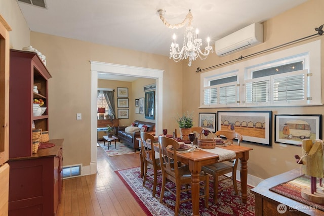 dining space featuring a wall mounted air conditioner, a chandelier, hardwood / wood-style flooring, and healthy amount of natural light