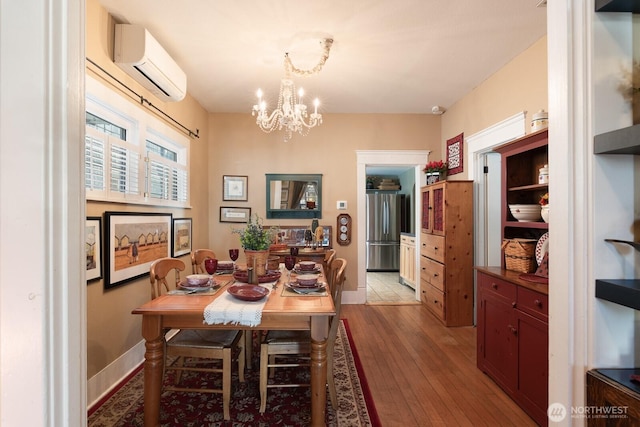 dining area with a wall mounted AC, a chandelier, and light wood-style flooring