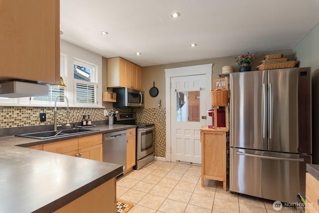 kitchen with stainless steel appliances, a sink, dark countertops, tasteful backsplash, and light tile patterned floors