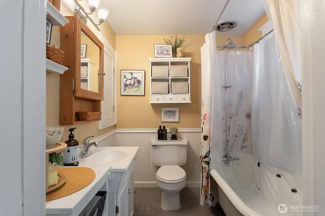 full bath featuring wainscoting, tile patterned flooring, toilet, shower / tub combo, and vanity