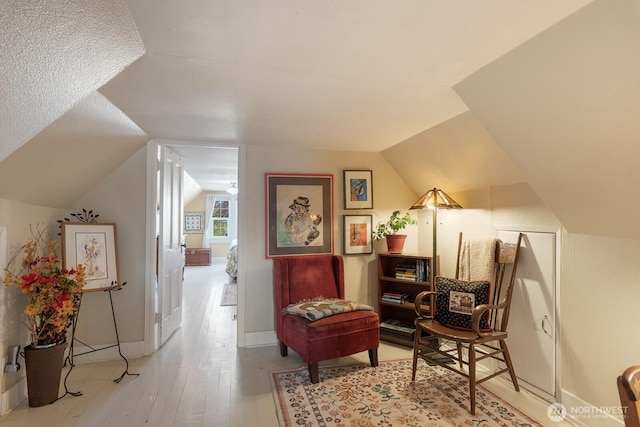living area featuring vaulted ceiling, wood finished floors, and baseboards