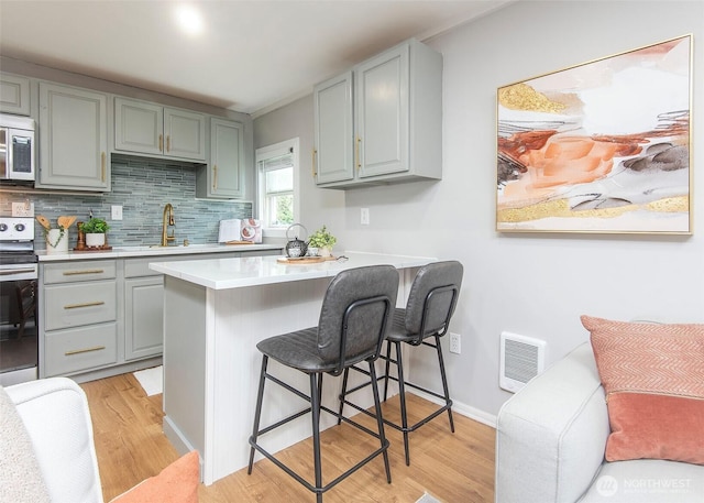 kitchen with visible vents, stainless steel microwave, electric range oven, gray cabinets, and a sink