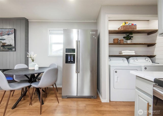 kitchen with washing machine and clothes dryer, open shelves, light countertops, light wood-style floors, and stainless steel fridge