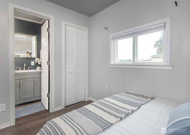 bedroom with a sink, a closet, connected bathroom, baseboards, and dark wood-style flooring