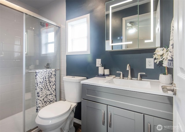 bathroom featuring a ceiling fan, vanity, toilet, and a shower stall