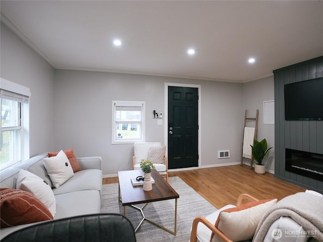 living room with a wealth of natural light, visible vents, recessed lighting, and light wood-type flooring