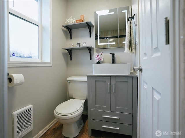 bathroom with baseboards, toilet, wood finished floors, heating unit, and vanity