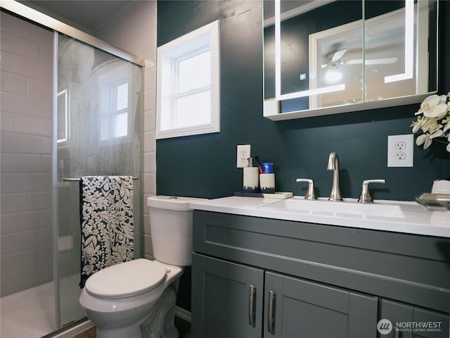 bathroom featuring a stall shower, toilet, vanity, and a ceiling fan