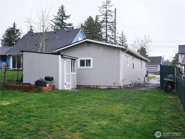 back of property with an outbuilding, a shed, a lawn, and fence