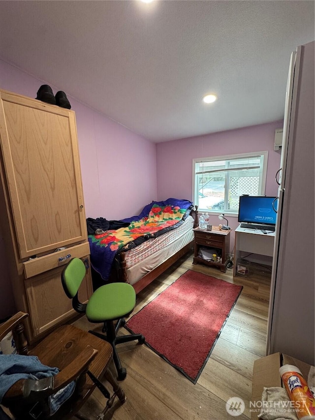 bedroom with a wall unit AC and wood finished floors