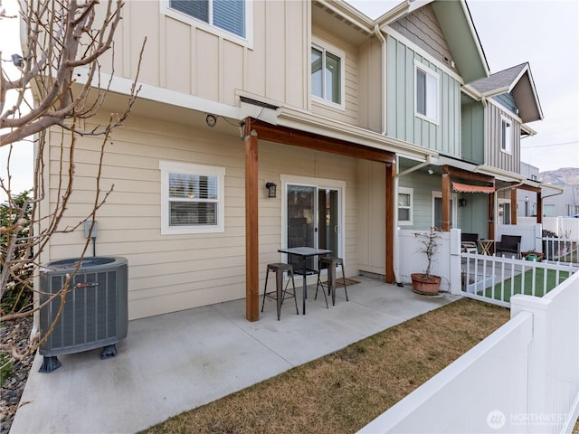 exterior space featuring a patio, central AC unit, board and batten siding, and fence private yard